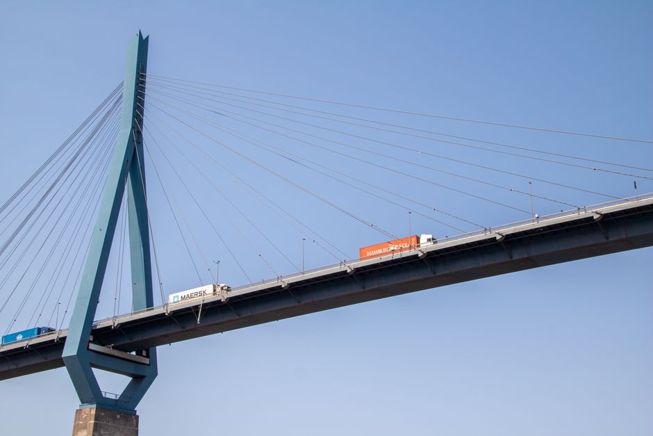 Trucks crossing the Köhlbrand Bridge in Hamburg, Germany, under a clear blue sky.